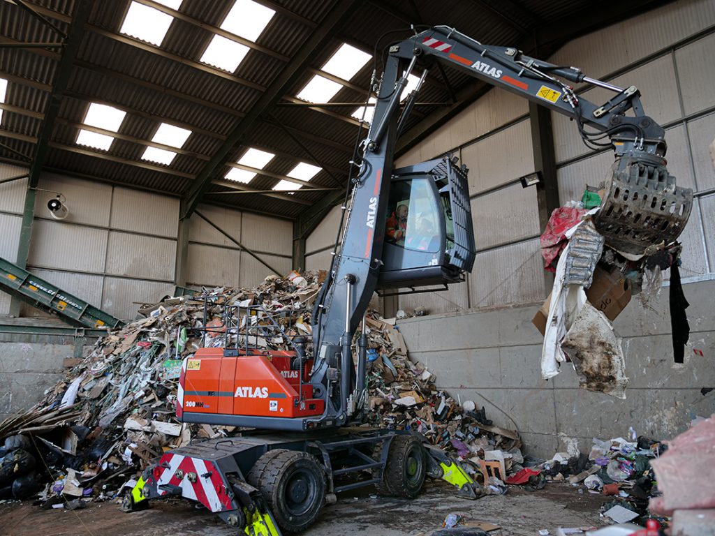 Atlas 200MH Material Handler with Selector Grab moving waste material at Banks Skip Hire Ltd